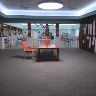 A modern lounge area featuring a table and two orange chairs, illuminated by soft overhead lighting.