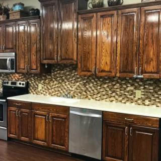A modern kitchen with wooden cabinets and a mosaic backsplash, featuring stainless steel appliances.