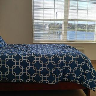 A bedroom with a blue-patterned bedspread and large window overlooking a scenic view.