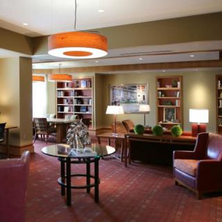 A cozy lounge area with comfortable seating, bookshelves, and warm lighting.