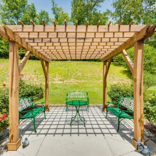 A wooden pergola with green patio furniture on a sunlit outdoor space.