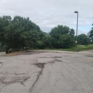 A deserted parking lot surrounded by trees on a cloudy day.