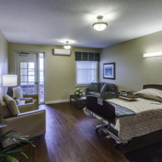 A well-furnished hospital or nursing home room with a bed, chair, and sofa.