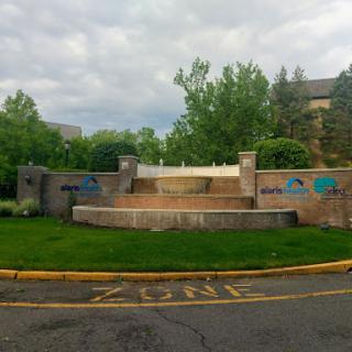 A serene outdoor fountain surrounded by lush greenery and steps leading up to it.