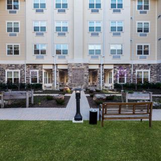 A residential apartment building with an outdoor landscaped garden and benches.