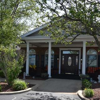 A welcoming building entrance with white columns and surrounding greenery.