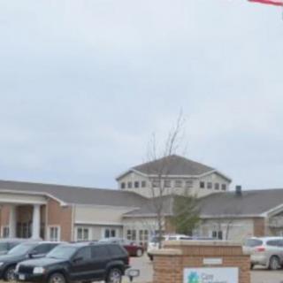 A view of a building with a parking lot full of cars on a cloudy day.