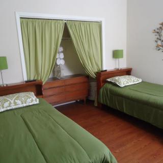 A cozy bedroom featuring twin beds with green bedding and minimalist decor.