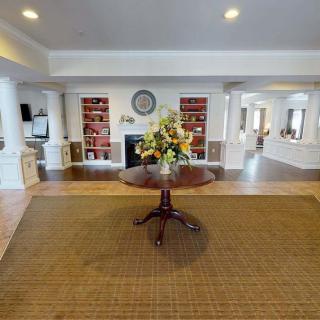 A spacious living area with a central table, bookshelves, and a fireplace.