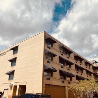 A view of a multi-story residential building under a cloud-filled sky.