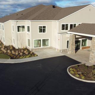 A modern residential building with a landscaped entrance and paved driveway.