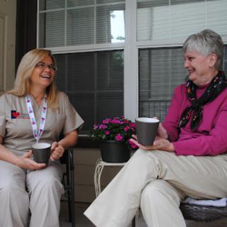 Two women enjoying a relaxed conversation with coffee on a porch.