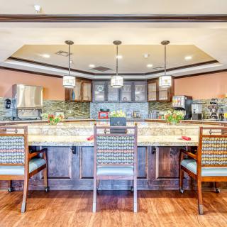 A modern kitchen interior with a wooden floor, countertop, and stylish chairs.