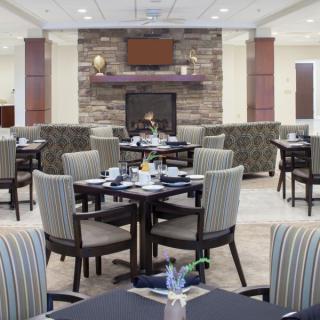 A cozy restaurant dining area with neatly arranged tables and a central fireplace.