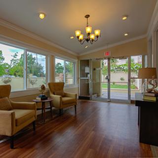 A cozy living room with comfortable seating, illuminated by a chandelier and filled with natural light.