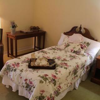 A cozy bedroom with a single bed adorned with floral bedding and classic wooden furniture.