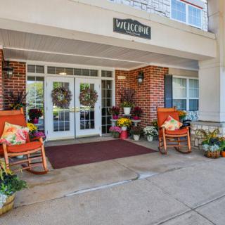 A welcoming building entrance with rocking chairs and decorative plants.