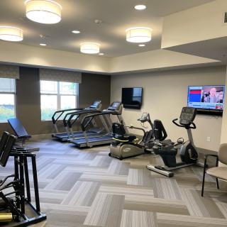 A modern gym with treadmills, stationary bikes, and televisions.
