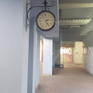 A wall-mounted clock in a bright, empty hallway.