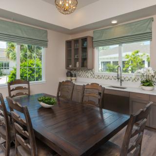 A modern dining room with a wooden table, chairs, and large windows allowing natural light in.
