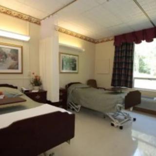 A clean hospital room with two beds and large windows.