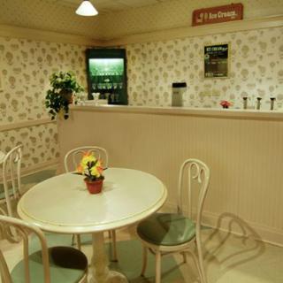 A quaint vintage caf interior with a round table and chairs, adorned with floral wallpaper and decorative elements.
