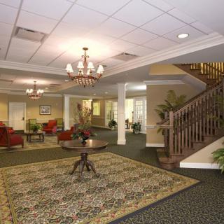 A well-furnished lobby with a chandelier, carpet, and seating area next to a staircase.