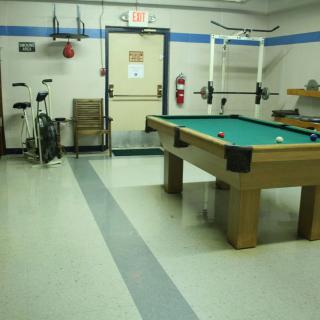 A multifunctional recreation room featuring a pool table and exercise equipment.