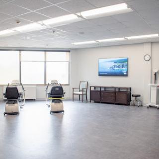 A spacious and modern waiting room in a medical facility, featuring comfortable chairs and a television.