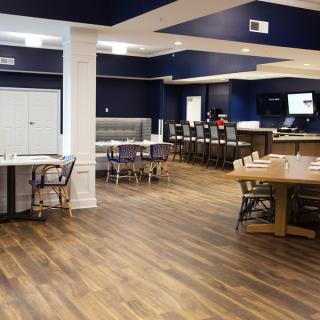 A modern restaurant interior featuring a spacious dining area with wooden floors and ample seating.