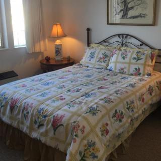 A cozy bedroom with floral bedding and a bedside lamp.