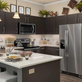A modern kitchen with stainless steel appliances, dark cabinets, and a central island for dining and preparation.