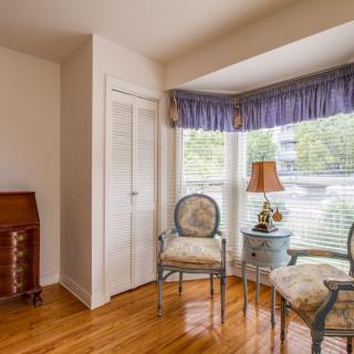 A cozy corner of a living room with antique chairs and a lamp by the window.