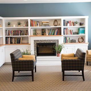 A cozy living room with bookshelves, a fireplace, and comfortable chairs.