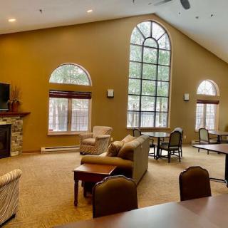 A spacious living room with high ceilings, large windows, and cozy seating arrangements near a fireplace.