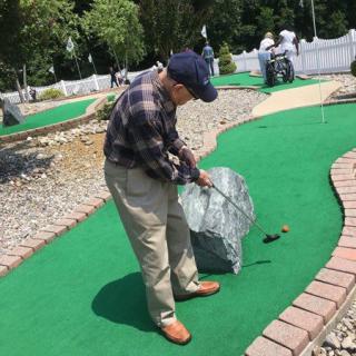 A man playing mini-golf outdoors.