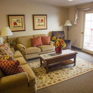 A cozy living room featuring a sofa, coffee table, and decorative elements such as artwork and lamps.