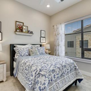 A cozy and well-decorated bedroom with a patterned bedspread, artwork, and large window.