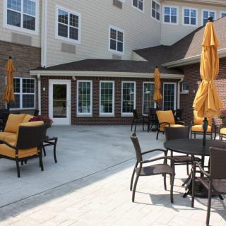 Outdoor patio area with tables, chairs, and umbrellas in front of a building.
