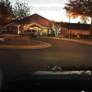 A car approaches a well-lit building entrance during the evening.