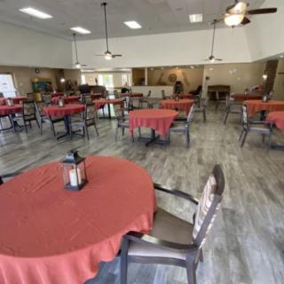 An empty dining area with tables covered in red tablecloths.