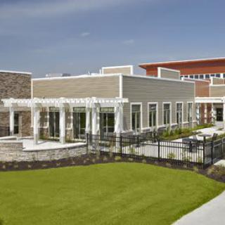 A modern building with a pergola and well-maintained lawn under a clear blue sky.