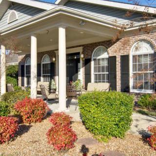 A charming house with a front porch, featuring columns and well-maintained landscaping.