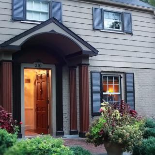 A welcoming house with a well-lit entrance and garden in the evening.