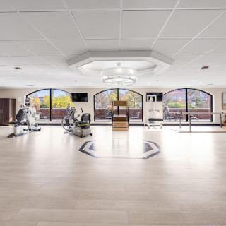 A spacious fitness center featuring modern exercise equipment and large windows that provide ample natural light.