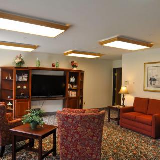 A cozy living room with a TV, shelves, and comfortable seating.