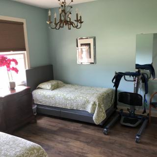 A tidy bedroom featuring two single beds, a chandelier, and exercise equipment on a wooden floor.