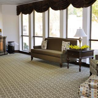 A cozy and inviting lobby area with a sofa, armchair, and natural light filtering through the windows.