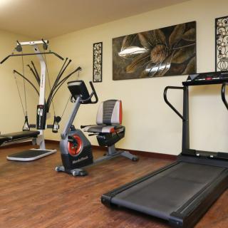 A compact home gym with various exercise equipment including a treadmill, stationary bike, and weight machine.