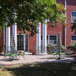 A courtyard patio with chairs and tables set up outside a brick building with large columns.